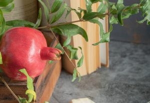Red pomegranate in wooden box with book and leaves. High quality photo